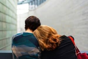 woman with red hair leaning on the shoulder of a man with dark hair in inpatient rehab